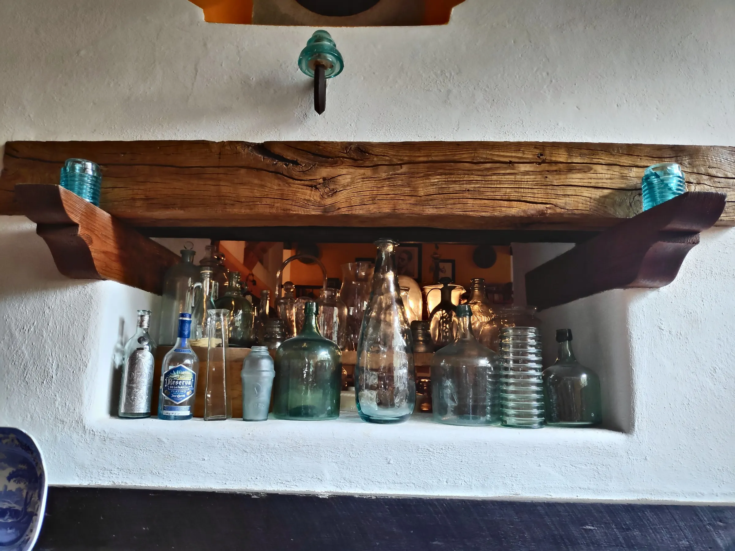 Niche with antique glass bottles beneath a wooden beam