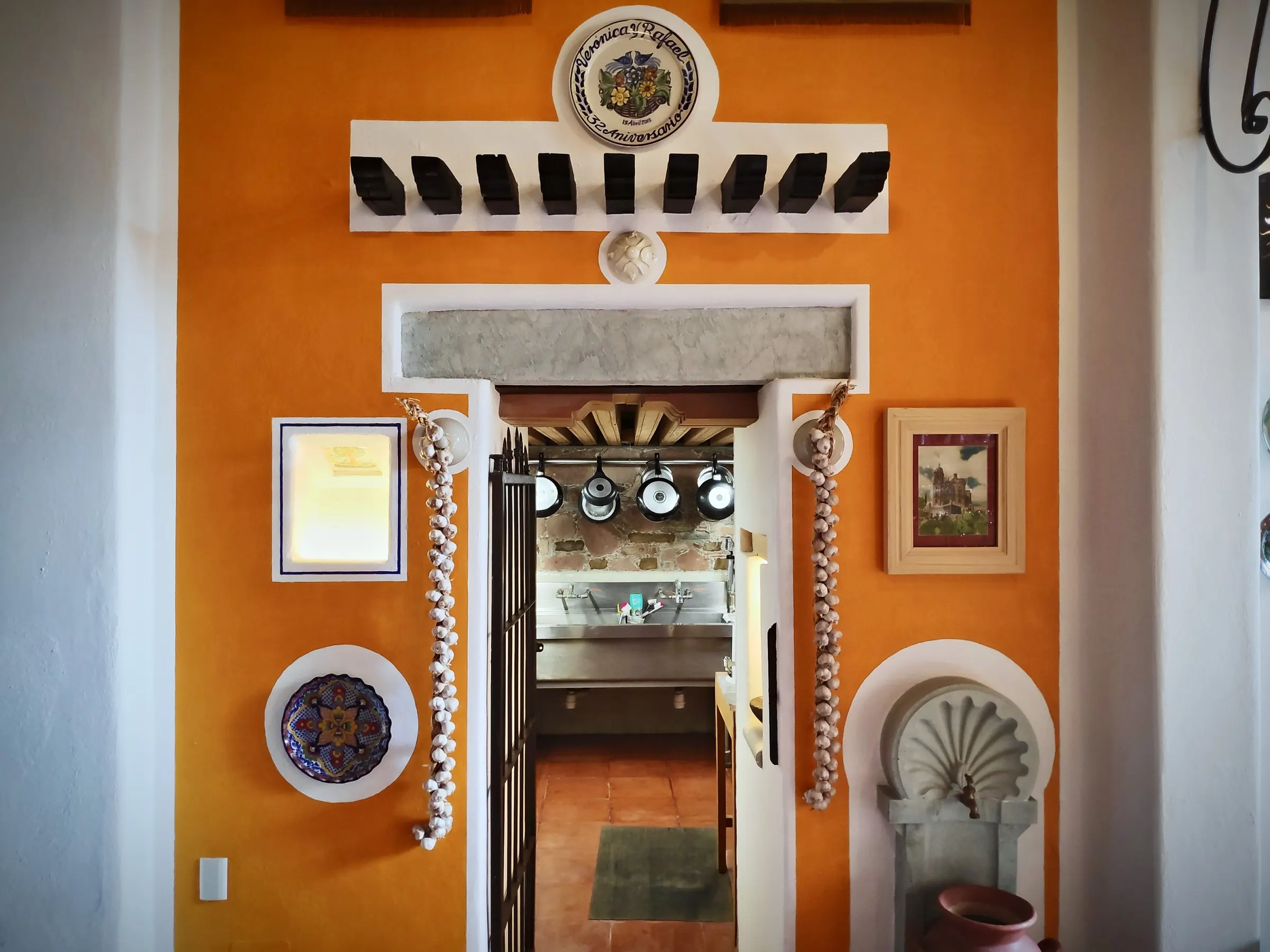 Orange wall with a shell fountain, garlic braids and the kitchen door