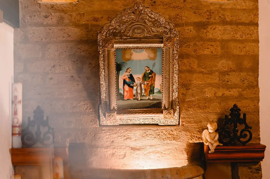 Painting of the Holy Family in a silver frame on a stone wall