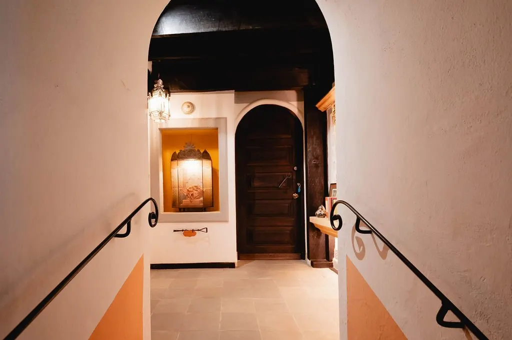 Staircase with iron handrail and arched wooden door