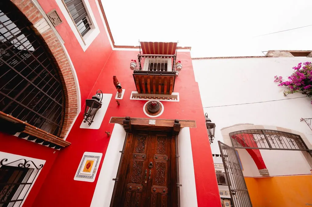 Red façade with balconies, carved wooden door and bougainvillea
