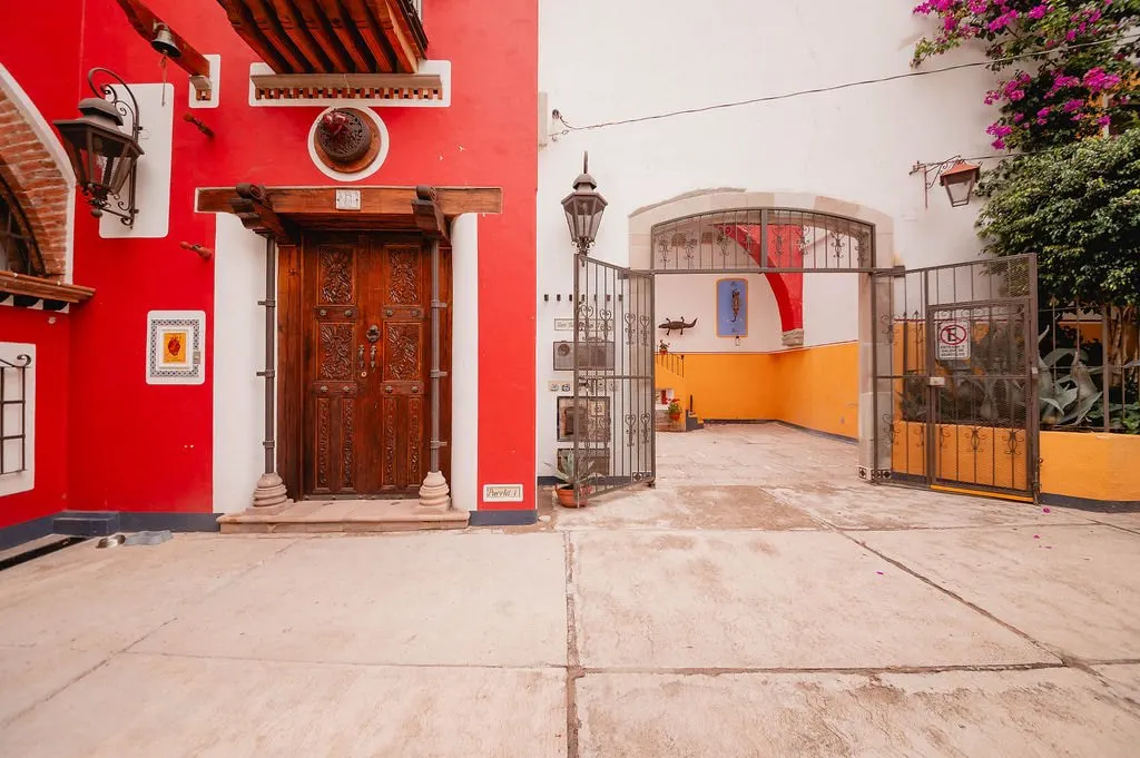 Entrance of Sanbernabé Tres: red façade, carved door and iron gate
