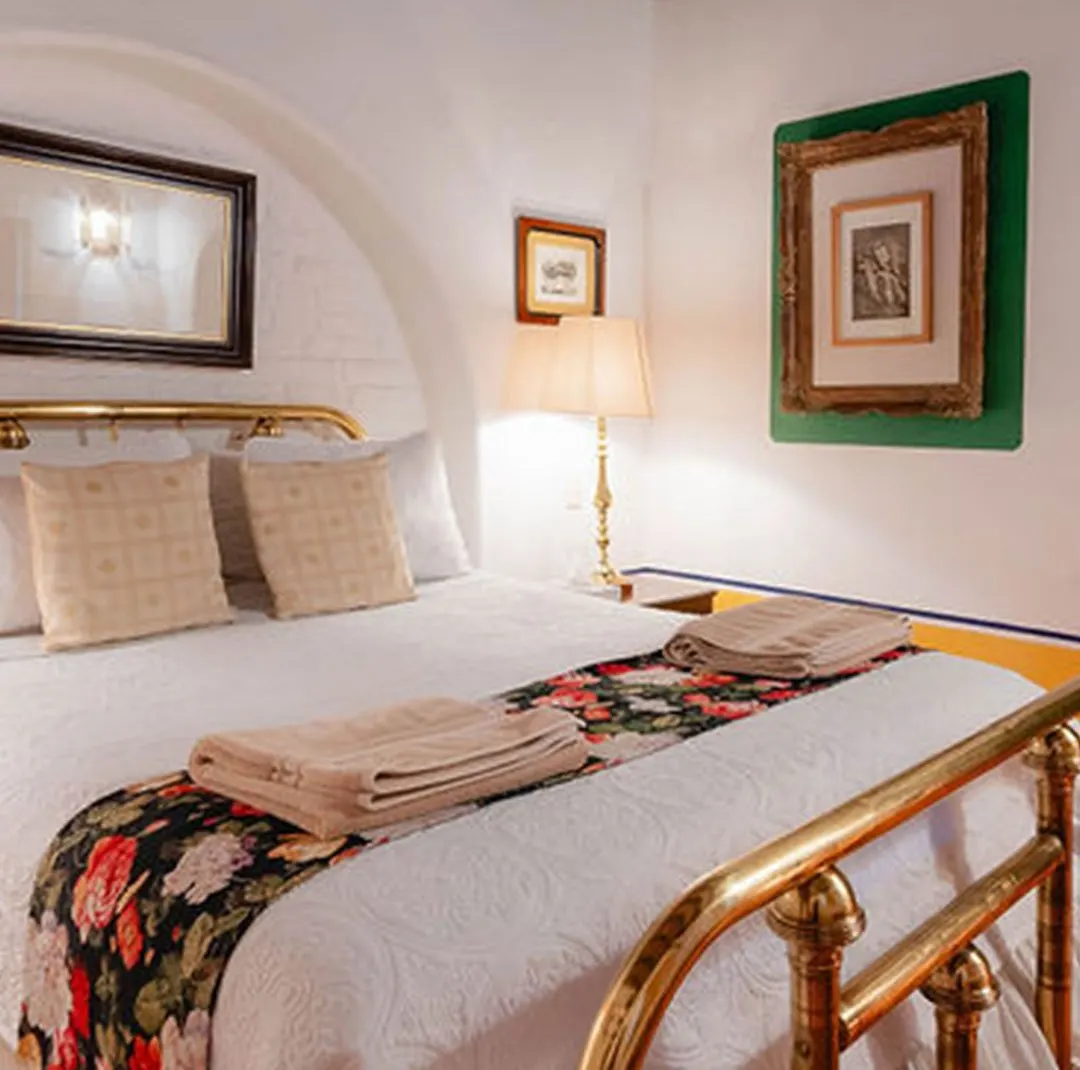 Chichíndaro suite with brass bed, arched wall and embroidered floral runner