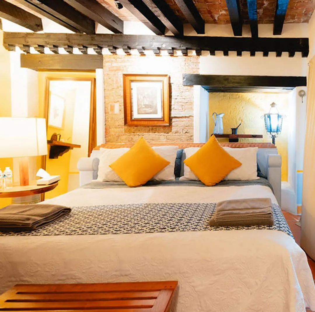 La Bolita suite with exposed brick wall, dark beams and ochre cushions