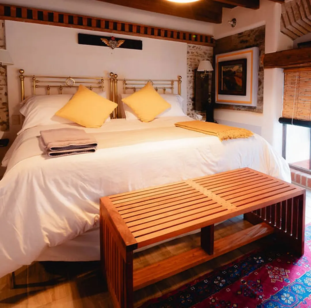 Marfil suite with brass headboard, honey-coloured cushions and wooden bench