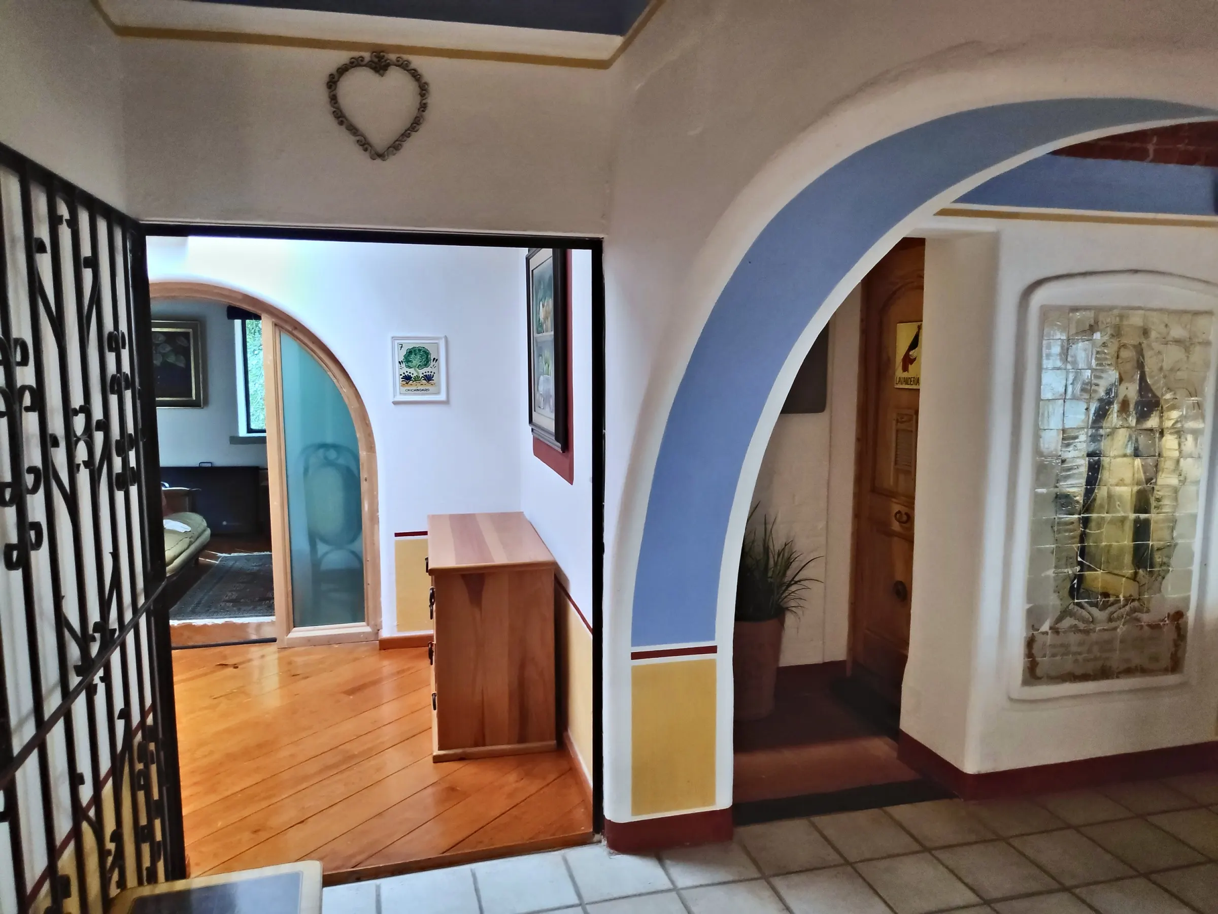 Passage with a blue arch, a wrought-iron grille and a tiled mural of the Virgin