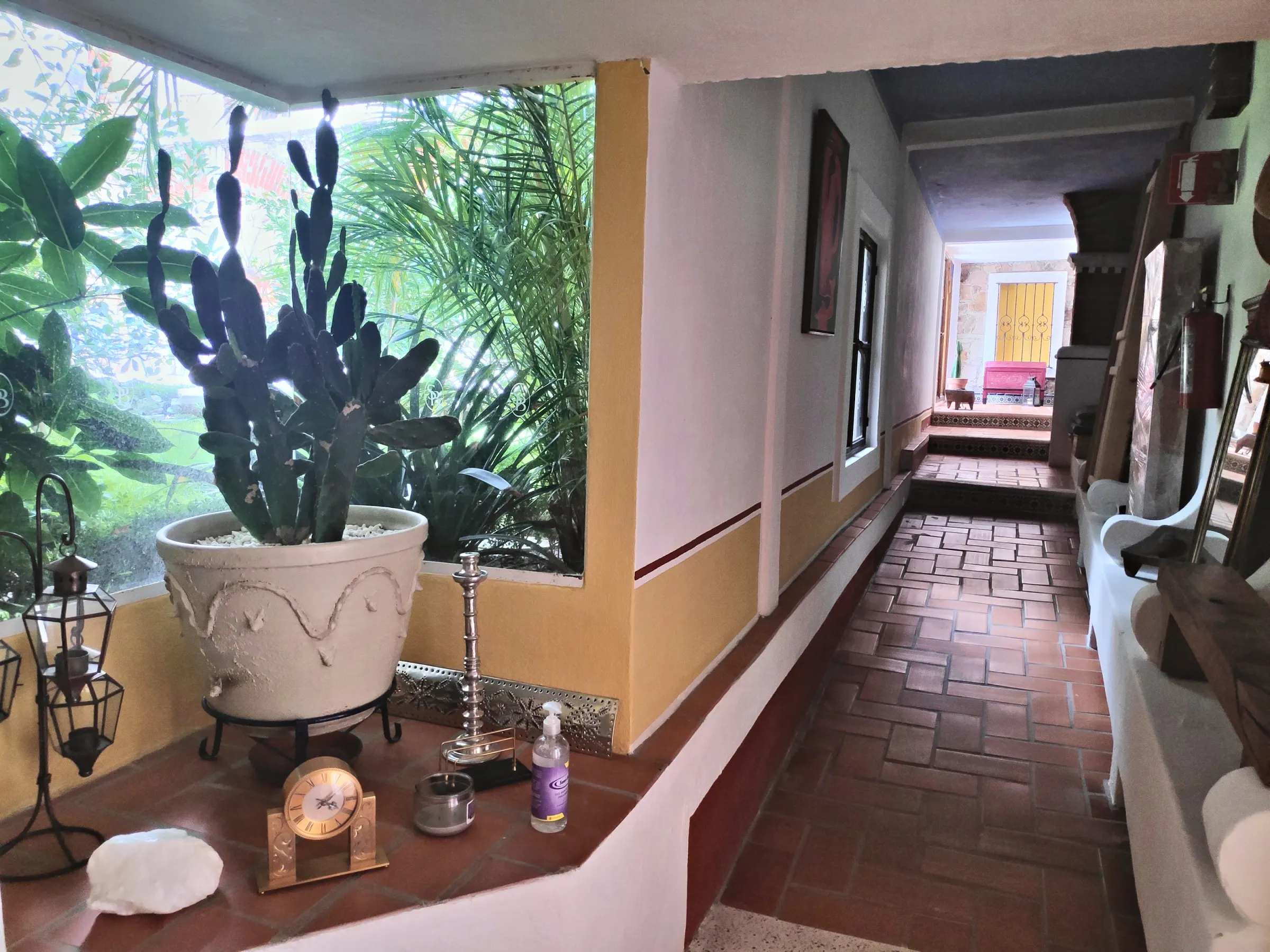 Corridor beside the garden, with a large potted prickly pear cactus and brick floor