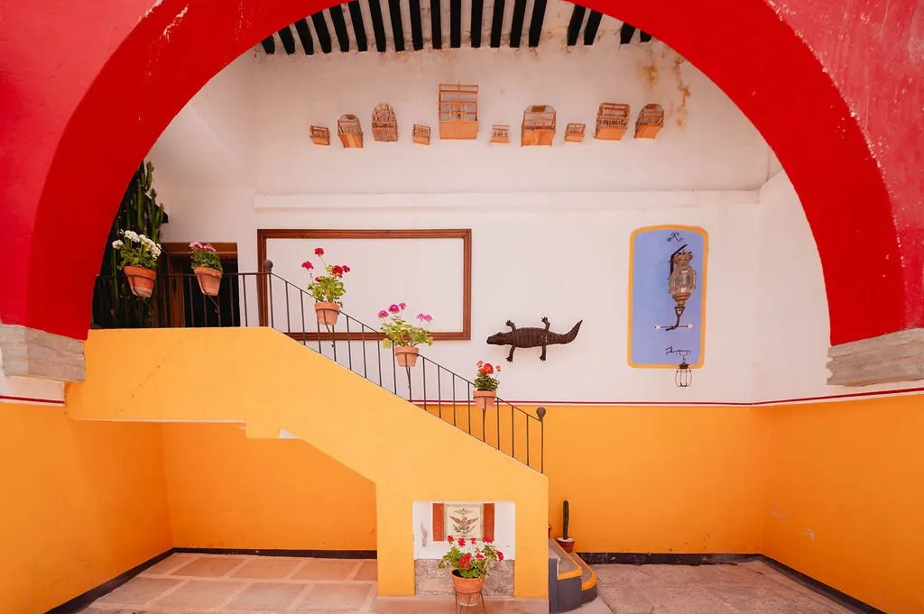 Courtyard with a red arch, yellow staircase and flower pots