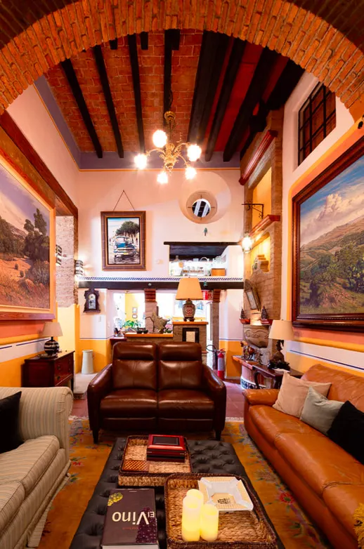 Living room beneath a brick arch and wooden beams, with chandelier