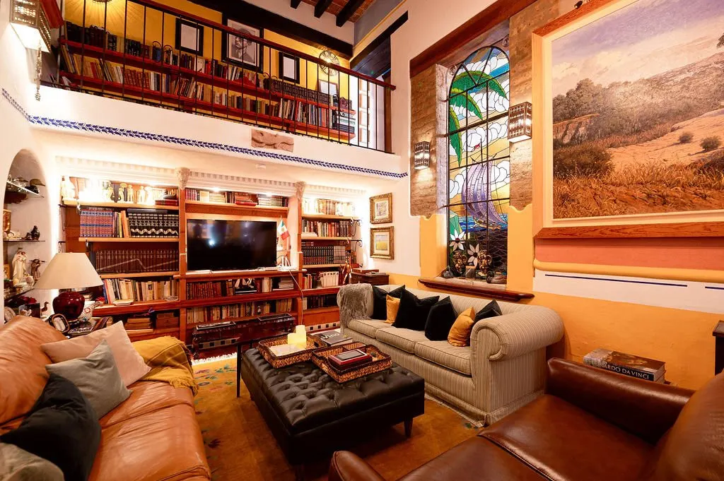 Double-height living room with library, stained-glass window and leather sofas