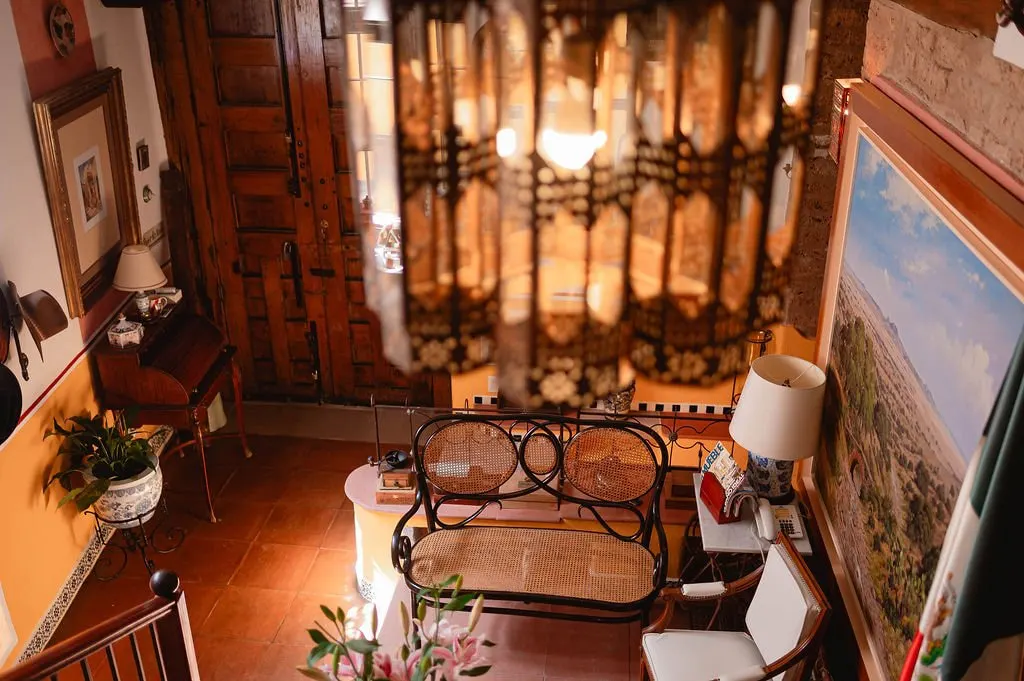 Sitting room with crystal chandelier, cane chairs and paintings
