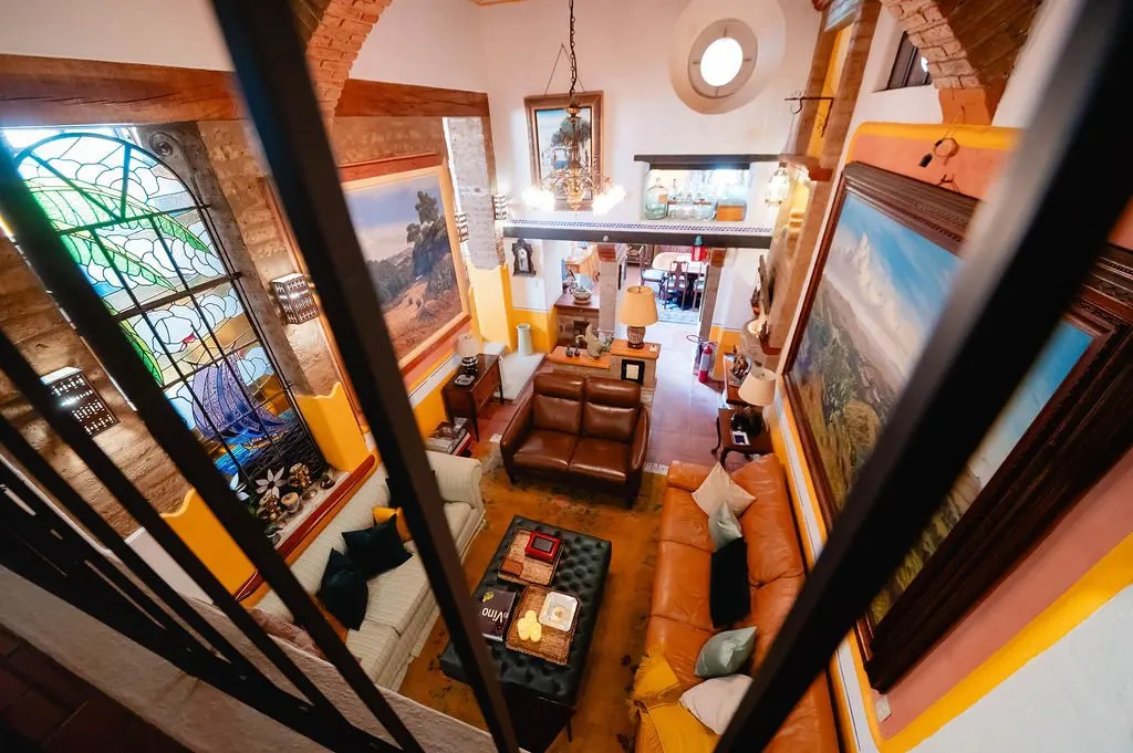 The double-height living room seen from the mezzanine railing