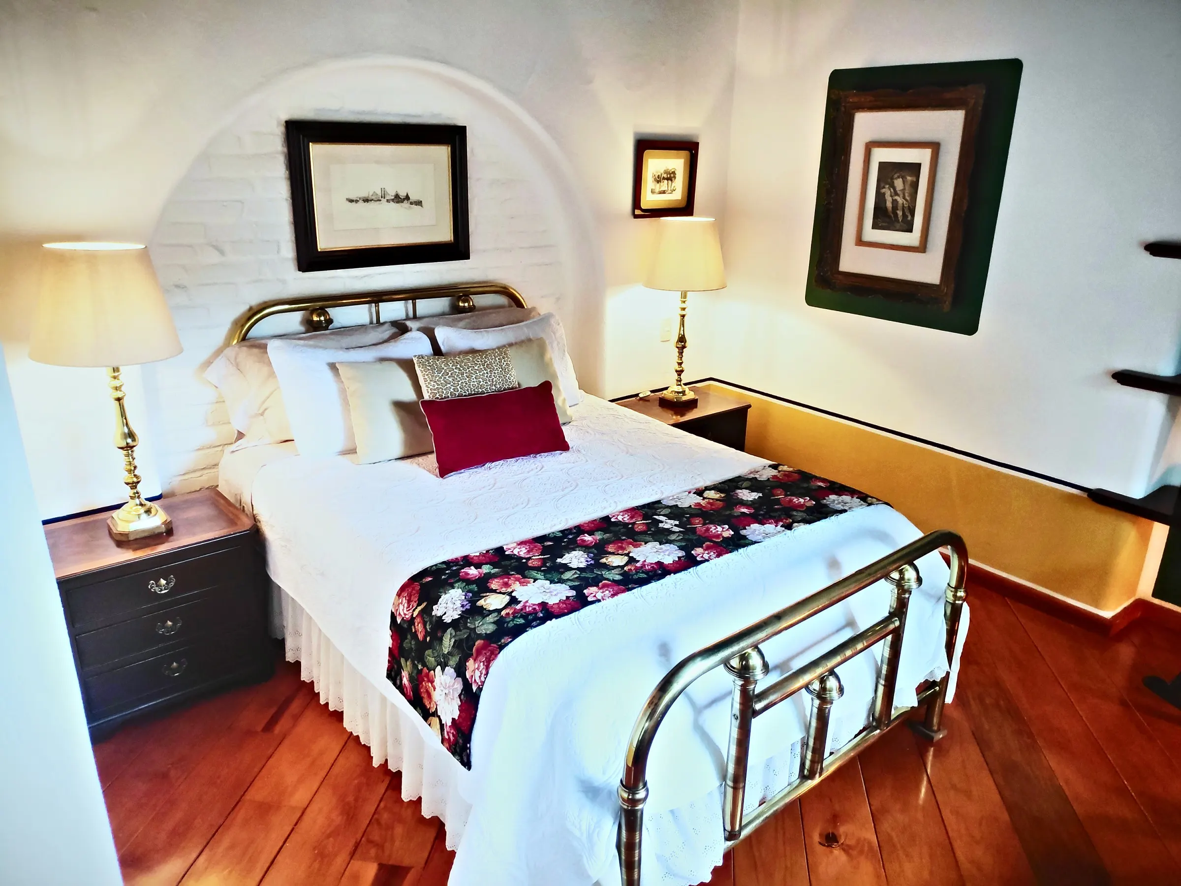 Chichíndaro suite: brass bed with an embroidered floral runner and golden lamps
