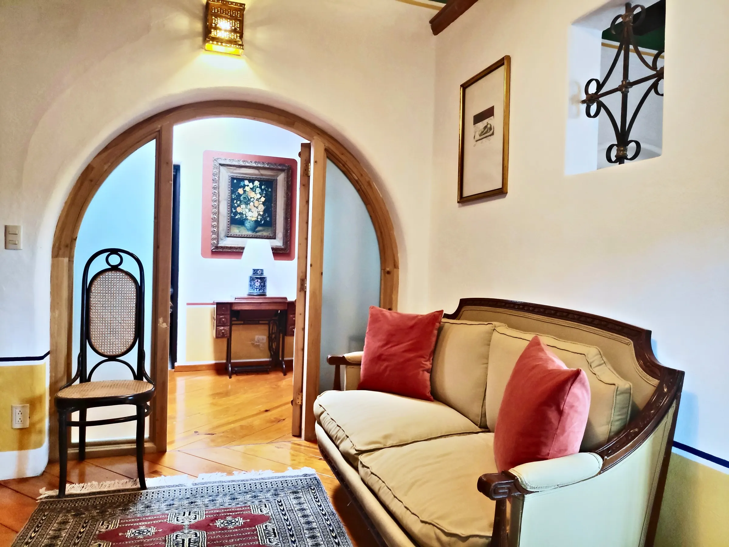 Sitting area of the Chichíndaro suite with a red-cushioned settee beneath a wooden arch