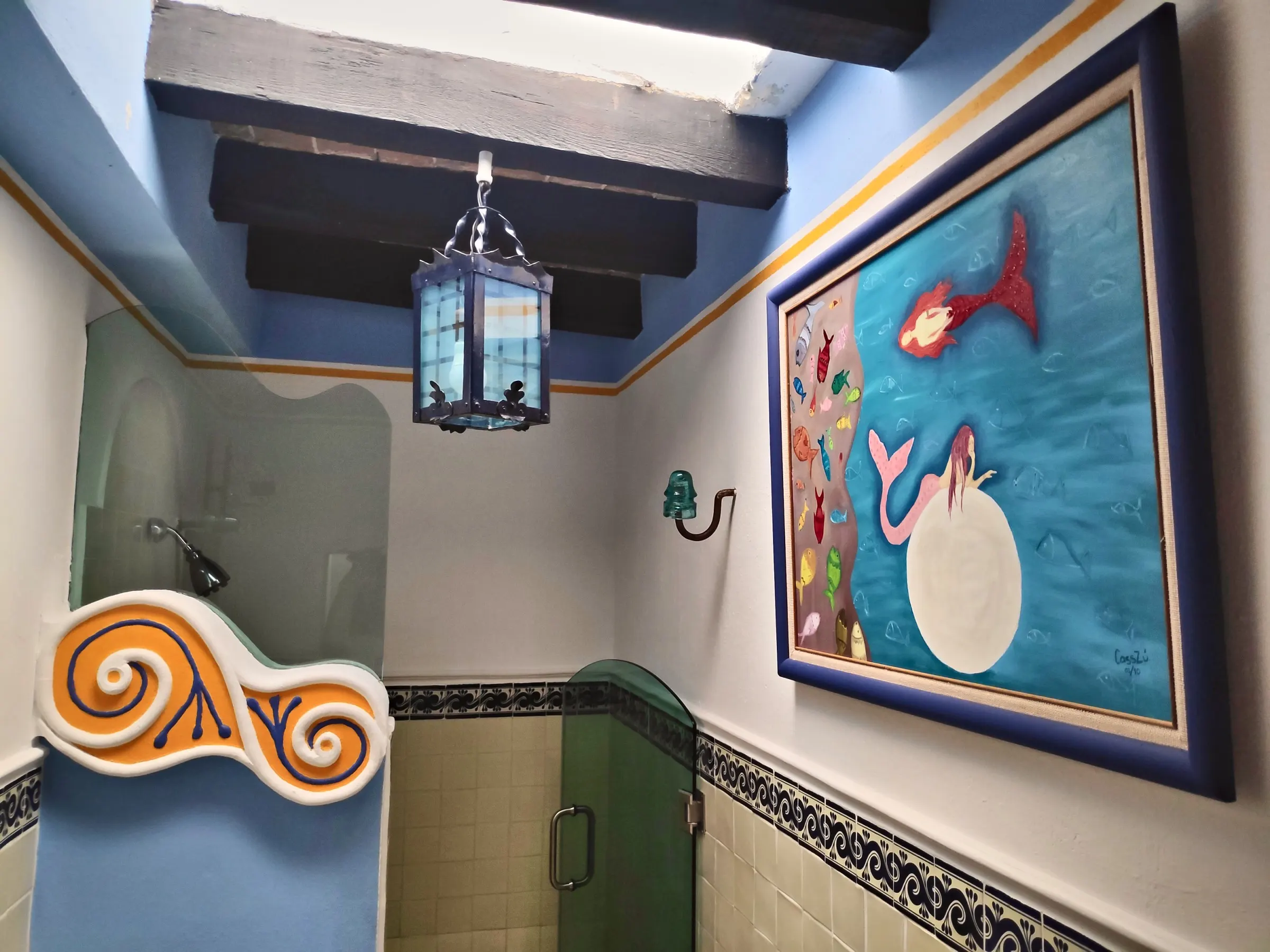 La Sirena suite bathroom with a mermaid painting and a blue lantern