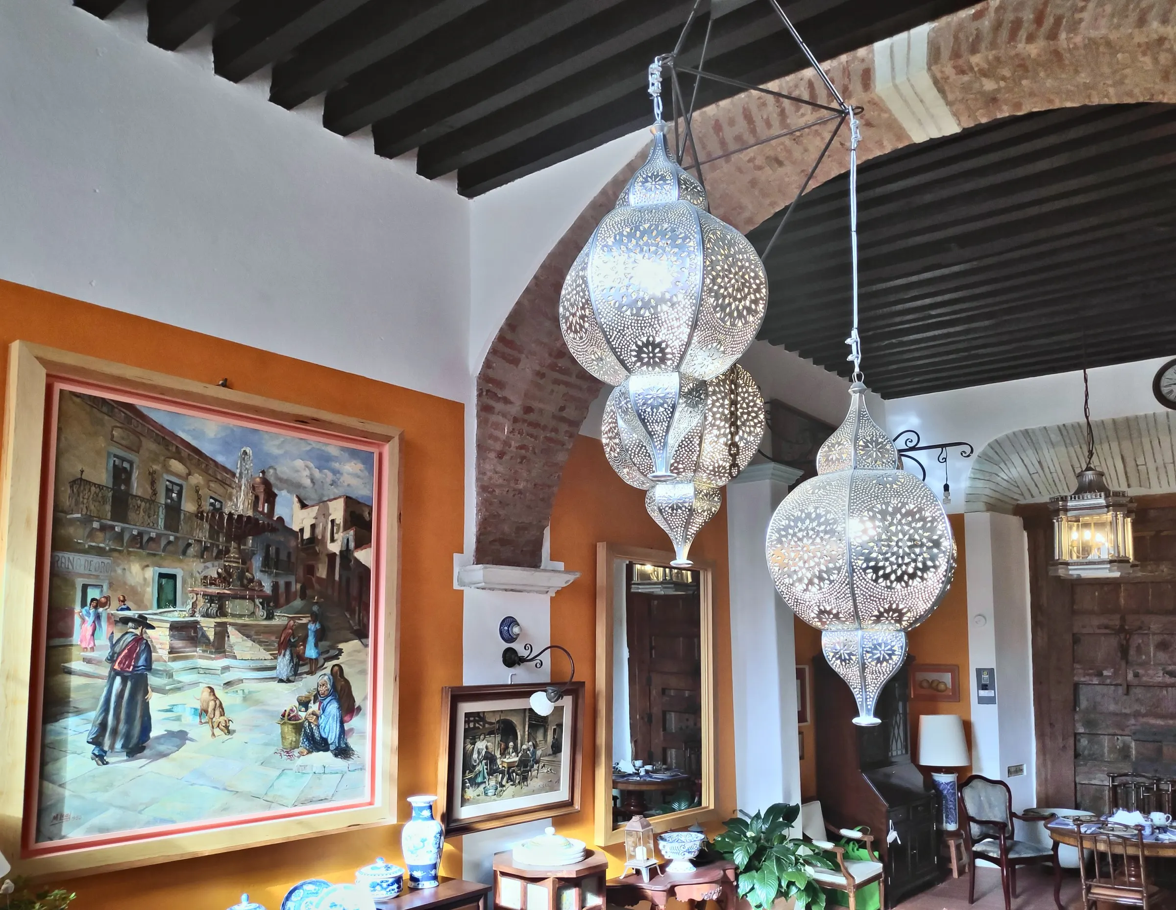 Hallway with pierced Moroccan lanterns and a painting of a colonial scene