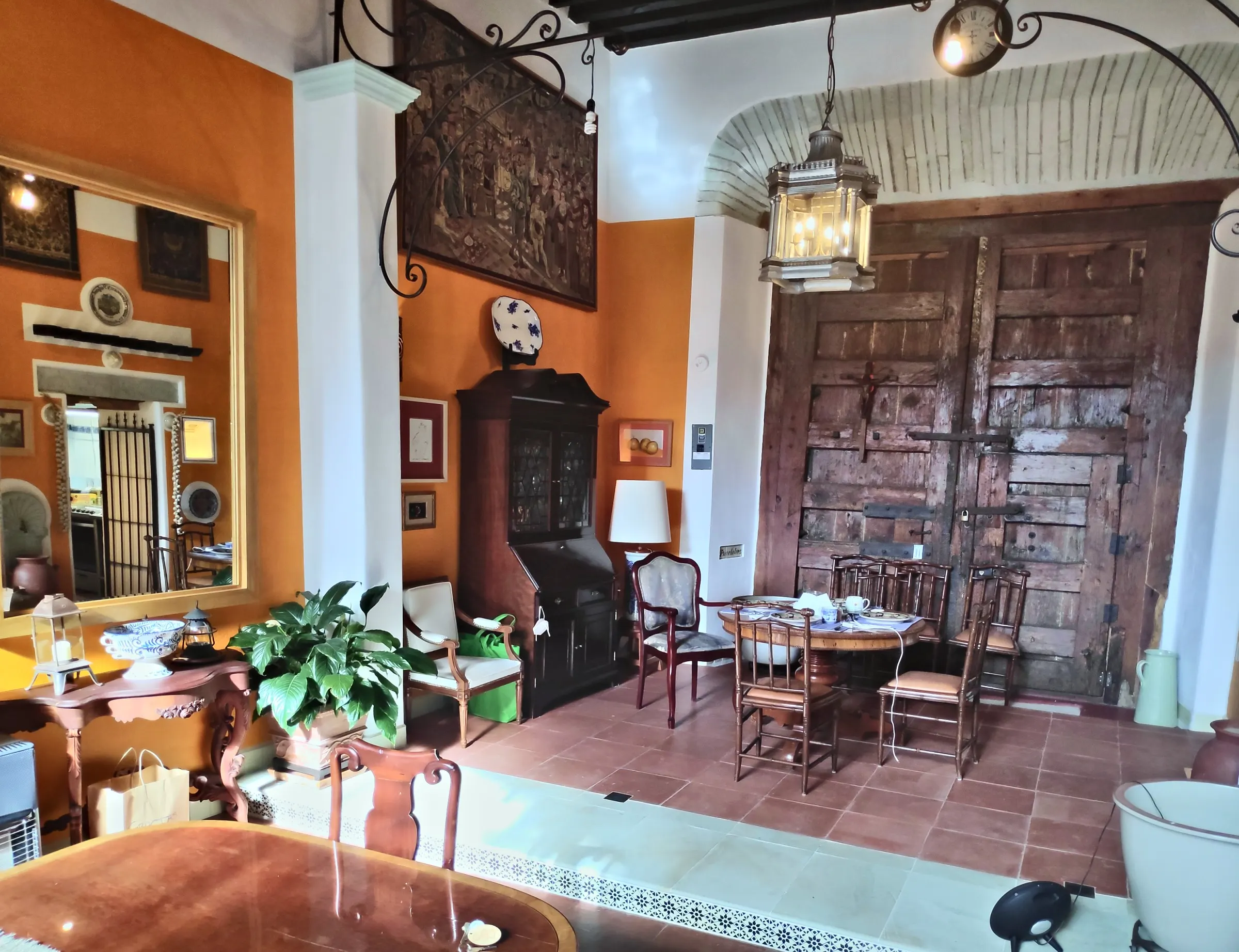 Entrance hall with orange walls, a gilded mirror and the old wooden gate
