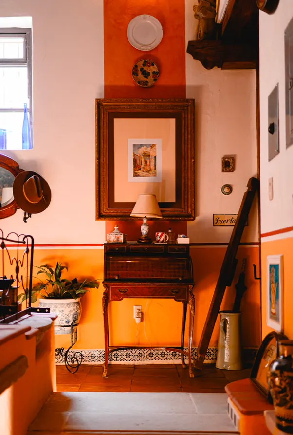 Hallway with an antique writing desk, lamp and orange-and-white walls